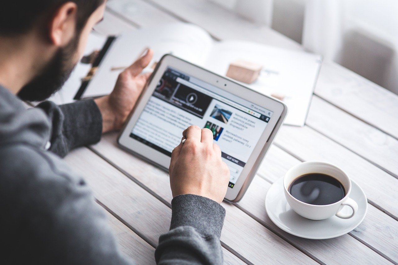 Man browsing through website on tablet, showcasing the importance of relevant content on good web design.